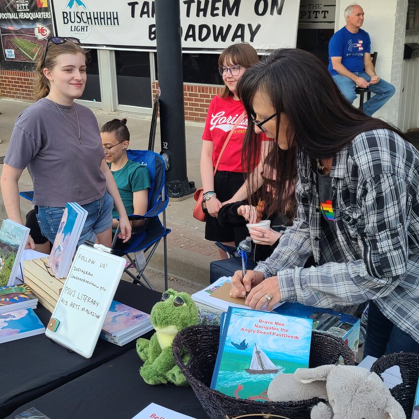 Laura Klipphahn-Wright, right, creates a poem on demand for a patron at the Cow Creek Review table as Mackenzie Clevenger, left, watches. Wright was one of several writers present at the Pittsburg ArtWalk April 12.