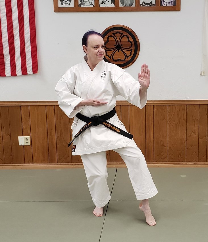 Nancey Konek practices a karate kata in front of the wall of honor at the Japan Karate-do Genbu-Kai dojo in Pittsburg. The wall includes photos and drawings of the lineage of the Shito-ryu style as well as American and Japanese flags.
