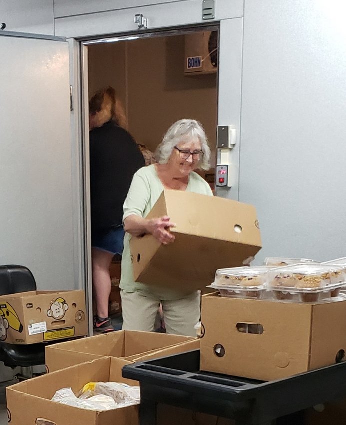 Volunteer Leeann Webb helps set out the day's allotment of donated meat at the Wesley House food bank.