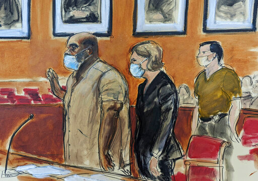 In this courtroom sketch, Frank James, left, the man accused in a mass shooting on a subway train in the Brooklyn borough of New York, is sworn-in during his arraignment in federal court, Friday, May 13, 2022, in New York. His defense attorney Mia Eisner-Grynberg is at center. James, 62, is facing charges of committing a terrorist attack or other violence against a mass transportation system and discharging a firearm during a violent crime. Both counts carry a maximum sentence of life in prison.  (AP Photo/Elizabeth Williams)