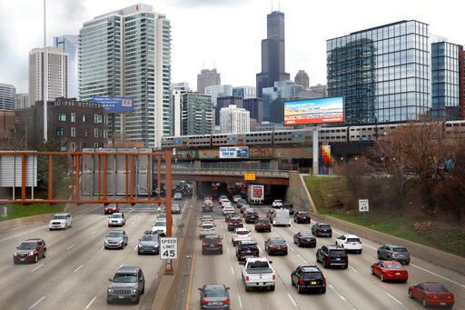 FILE - Traffic flows along Interstate 90 highway as a Metra suburban commuter train moves along an elevated track in Chicago on March 31, 2021.   With upcoming data showing traffic deaths soaring, the Biden administration is steering $5 billion in federal aid to cities and localities to address the growing crisis by slowing down cars, carving out bike paths and wider sidewalks, and nudging commuters to public transit.  (AP Photo/Shafkat Anowar, File)