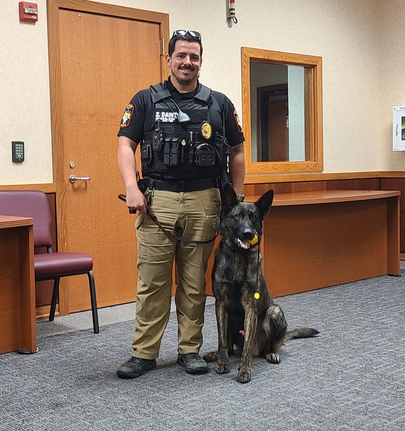 After playing with his favorite toy, K-9 Officer Rone, right, obeys a command from his handler, Officer Zack Dainty, left, to sit patiently.