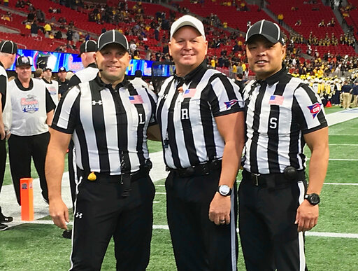 In this Dec. 29, 2018 photo provided by Lo van Pham, from left, line judge Derek Anderson,  referee Mike Defee and side judge Lo van Pham pose for a photo before the Peach Bowl NCAA college football game in Atlanta. Lo van Pham&rsquo;s journey to the NFL began when he fell in love with sports upon arriving in Texas after living in refugee camps with his family. More than 40 years later, van Pham is set to become the first Asian American to officiate in the NFL. (Lo van Pham/NFL via AP)