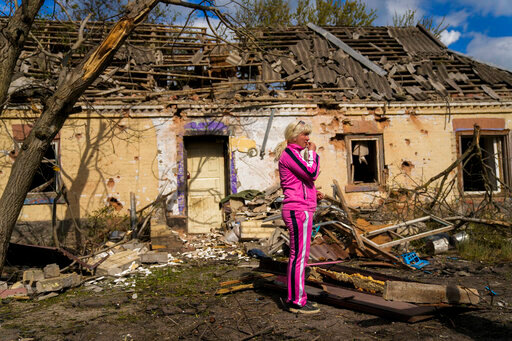 Iryna Martsyniuk, 50, stands next to her house, heavily damaged after a Russian bombing in Velyka Kostromka village, Ukraine, Thursday, May 19, 2022. Martsyniuk and her three young children were at home when the attack occurred in the village, a few kilometres from the front lines, but they all survived unharmed. (AP Photo/Francisco Seco)