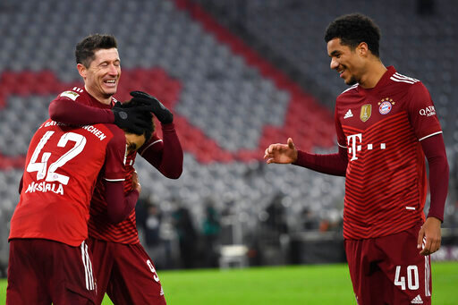 FILE - Bayern Munich's Robert Lewandowski, center, celebrates with teammates Jamal Musiala, left, and Malik Tillman, right, after scoring his side's fourth goal during a German Bundesliga soccer match against VfL Wolfsburg at the Allianz Arena in Munich, Germany, Dec. 17, 2021. Bayern Munich midfielder Tillman is switching affiliation from Germany to the United States and is among 27 players invited to the Americans&rsquo; next-to-last training camp ahead of the World Cup. (AP Photo/Andreas Schaad, File)