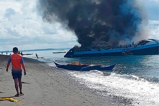 In this handout provided by the Philippine Coast Guard, smoke billows from ferry M/V Mercraft 2 as it's towed to an island off of the town of Real, Quezon province, Philippines on Monday, May 23, 2022. The passenger ship caught fire as it neared it's port destination in Real, killing several people on board. (Philippine Coast Guard via AP Photo)