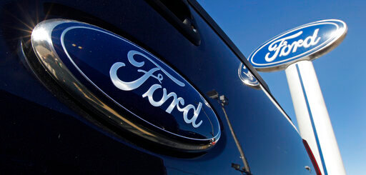FILE - A Ford logo, on the tailgate of a 2012 F350 Super Duty pick-up truck, and Ford dealership sign are displayed at Salem Ford in Salem, N.H., on Oct. 25, 2011. Ford Motor Company on Tuesday,May 24, 2022, settled claims by 40 U.S. state attorneys general that the company made misleading claims about the fuel economy and payload capacity of some of its vehicles, violating state consumer protection laws. (AP Photo/Charles Krupa, File)
