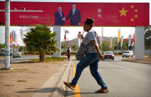 FILE - A woman crosses the street near a billboard commemorating the state visit of Chinese President Xi Jinping in Port Moresby, Papua New Guinea, Nov. 15, 2018. China wants 10 small Pacific nations to endorse a sweeping agreement covering everything from security to fisheries in what one leader warns is a &ldquo;game-changing&rdquo; bid by Beijing to wrest control of the region. (AP Photo/Mark Schiefelbein, File)