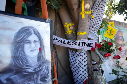 Yellow tape marks bullet holes on a tree and a portrait and flowers create a makeshift memorial at the site where Palestinian-American Al-Jazeera journalist Shireen Abu Akleh was shot and killed in the West Bank city of Jenin, Thursday,, May 19, 2022. Almost two weeks after the death of Abu Akleh, a reconstruction by The Associated Press lends support to assertions from both Palestinian authorities and Abu Akleh's colleagues that the bullet that cut her down came from an Israeli gun. (AP Photo/Majdi Mohammed)