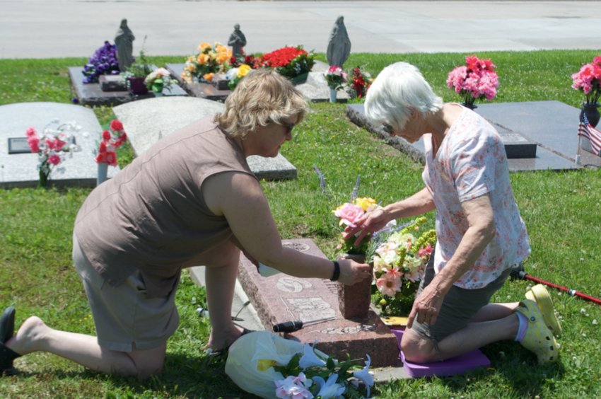 On Monday, Gwyn Armendariz, left, and Marilyn Jones arrange flowers on Jones&rsquo; parents' graves at Highland Park Cemetery. Jones said her father was in the Navy. Many families gathered to honor their loved ones on Memorial Day.