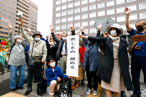 A group of plaintiffs and their supporters celebrate a court decision outside the Sapporo district court Tuesday, May 31, 2022 in Sapporo, Hokkaido prefecture, Japan. The court Tuesday ordered that Hokkaido Electric Power Co. not restart a nuclear power plant because it lacks adequate tsunami safeguards, backing residents&rsquo; safety concerns at a time the government is pushing shutdown reactors to resume power generation after pledging to ban imports of Russian fossil fuels. (Yohei Fukai/Kyodo News via AP)