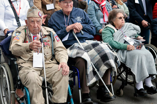 US WWII veteran Ray Wallace, of the 507th PIR 82rd Airborne, looks on as World War II history enthusiasts parade in WWII vehicles to commemorate the 78th anniversary of D-Day that led to the liberation of France and Europe from the German occupation, in Sainte-Mere-L'Eglise, Normandy, Sunday, June, 5, 2022. On Monday, the Normandy American Cemetery and Memorial, home to the gravesites of 9,386 who died fighting on D-Day and in the operations that followed, will host U.S. veterans and thousands of visitors in its first major public ceremony since 2019. (AP Photo/Jeremias Gonzalez)