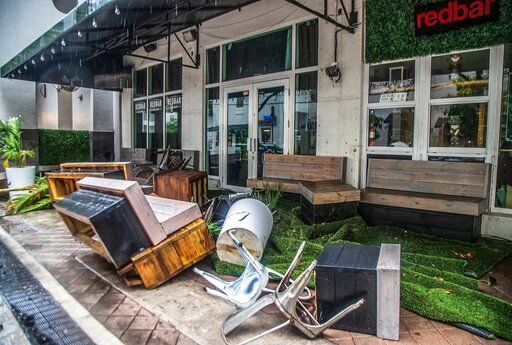 Furniture and plants from the RedBar Brickell bar litter the sidewalk after rainfall from Tropical Storm Alex caused flooding Saturday, June 4, 2022, in the Brickell area near downtown Miami. (Pedro Portal/Miami Herald via AP)