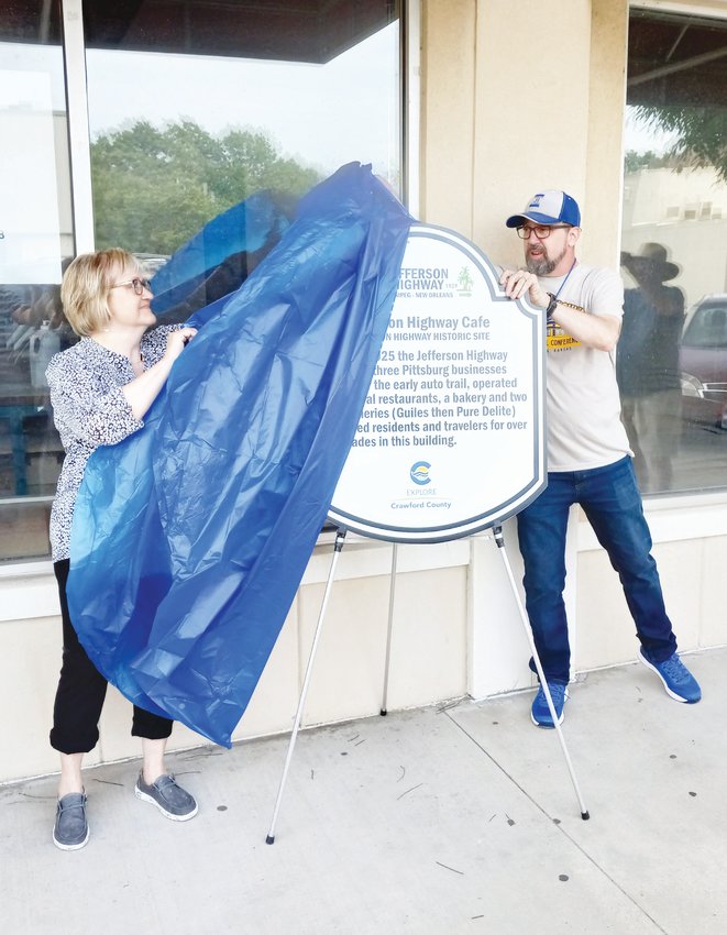 Sandy Myers, left, whose grandfather owned the Jefferson Highway Caf&eacute; in the 1920s, and Jefferson Highway Association President Roger Bell unveil a new sign on Saturday commemorating the history of the building at 816 N. Broadway that formerly housed the caf&eacute;.