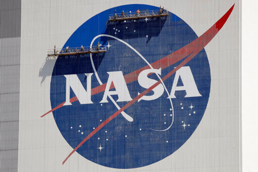 FILE - Workers on scaffolding repaint the NASA logo near the top of the Vehicle Assembly Building at the Kennedy Space Center in Cape Canaveral, Fla., Wednesday, May 20, 2020. On Thursday, June 9, 2022, NASA announced it is launching a study of UFOs as part of a new push toward high-risk, high-impact science, setting up an independent team to see how much information is publicly available on the matter and how much more is needed. (AP Photo/John Raoux, File)