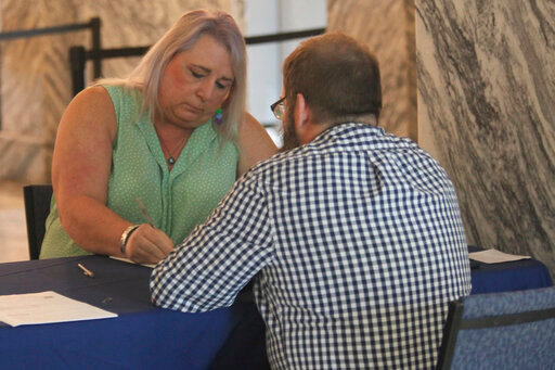 Kansas state Rep. Stephanie Byers, left, D-Wichita, fills out paperwork for Bryan Caskey, state elections director, to withdraw as a candidate for reelection, Friday, June 10, 2022, at the Kansas secretary of state's office in Topeka, Kan. Byers was the first transgender state legislator and said she is moving to Texas to help care for her wife's aging parents. (AP Photo/John Hanna)