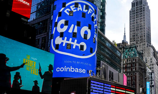 FILE - An advertisement for Coinbase, center, is displayed on NASDAQ billboard in Times Square, New York, Thursday, Nov. 4, 2021. Coinbase Global says, Tuesday, June 14, 2022,  it plans to cut about 1,100 jobs, or approximately 18% of its global workforce, as part of a restructuring in order to help manage its operating expenses in response to current market conditions. The company said in a regulatory filing that it expects to have about 5,000 total employees at the end of its current fiscal quarter on June 30.  (AP Photo/Seth Wenig, File)