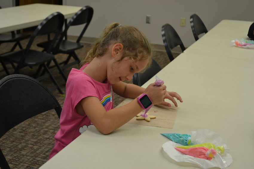 Aubrey Zagonel frosts a starfish shaped cookie during the Girard Public Library&rsquo;s Family Cookie Night event on Monday. The library made ocean themed sugar cookies to go with its summer reading theme and allowed the attendees to frost them using several different colors of frosting.