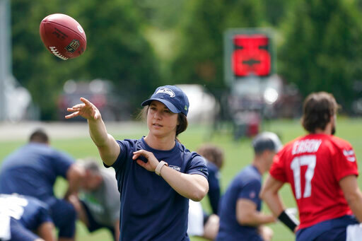 Amanda Ruller, who is currently working as an assistant running backs coach for the NFL football Seattle Seahawks through the league's Bill Walsh Diversity Fellowship program, passes a football during NFL football practice on June 8, 2022, in Renton, Wash. Ruller's job is scheduled to run through the Seahawks' second preseason game in August. (AP Photo/Ted S. Warren)