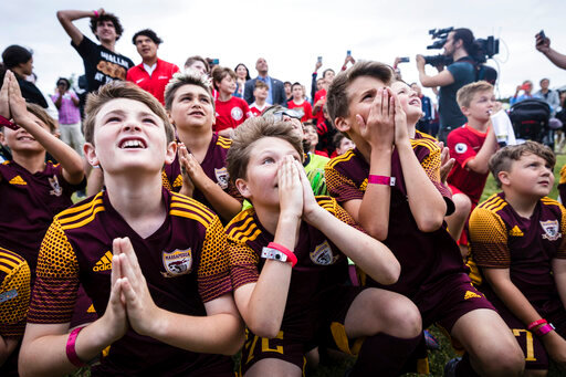 Children from the Massapequa youth soccer team wait for an announcement of host cities, at a 2026 FIFA World Cup host city selection watch party at Liberty State Park in Jersey City, N.J., Thursday, June 16, 2022. (AP Photo/Stefan Jeremiah)