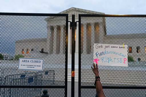 FILE - A demonstrator places a sign on the anti-scaling fence outside of the U.S. Supreme Court, Thursday, May 5, 2022 in Washington. As the United States Supreme Court appears poised to overturn Roe v. Wade, Muslim Americans are gearing up for what the landmark reversal could mean for their communities. (AP Photo/Alex Brandon, File)