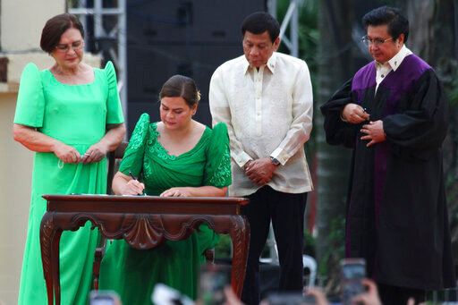 Sara Duterte, daughter of outgoing populist president of the Philippines, signs documents during her oath taking as vice president in her hometown in Davao city, southern Philippines, Sunday, June 19, 2022. Duterte clinched a landslide electoral victory despite her father's human rights record that saw thousands of drug suspects gunned down. Also in photo are, from left, her mother Elizabeth Zimmerman, Philippine President Rodrigo Duterte and Supreme Court Justice Ramon Paul Hernando. (AP Photo/Manman Dejeto)