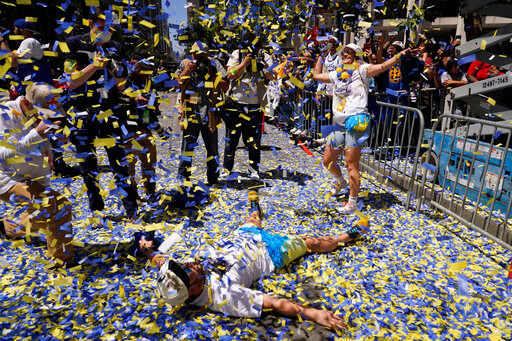 A man lays on Market Street as confetti rains during the Golden State Warriors NBA championship parade in San Francisco, Monday, June 20, 2022. (AP Photo/Eric Risberg)