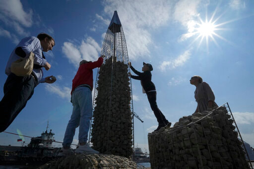 FILE - People build a model of the business tower Lakhta Centre, at the headquarters of Russian gas monopoly Gazprom, filling the frame with stones, in St. Petersburg, Russia, Thursday, June 9, 2022. It's not a summer heat wave that's making European leaders and businesses sweat. It's fear that Russia's manipulation of natural gas supplies will lead to an economic and political crisis next winter. Or, in the worst case, even sooner. (AP Photo/Dmitri Lovetsky, File)