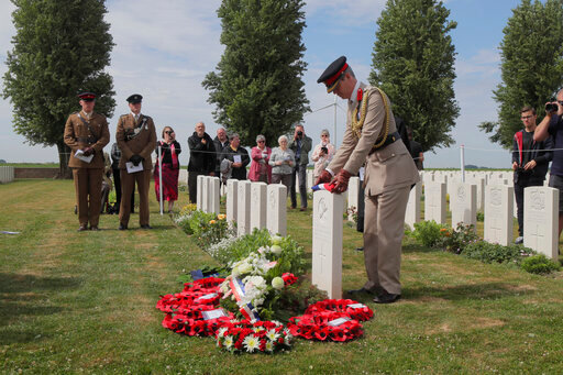 Colonel Howard Wilkinson, Military Attache, British Embassy Paris, puts a French flag on the grave of Second Lieutnant Osmund Bartle Wordsworth during a Rededication Service, in the cemetery of Ecoust-Saint-Mein, northern France, Tuesday, June. 21, 2022. Wordsworth was killed in action at the Battle of Arras on April 2, 1917. (AP Photo/Michel Spingler)