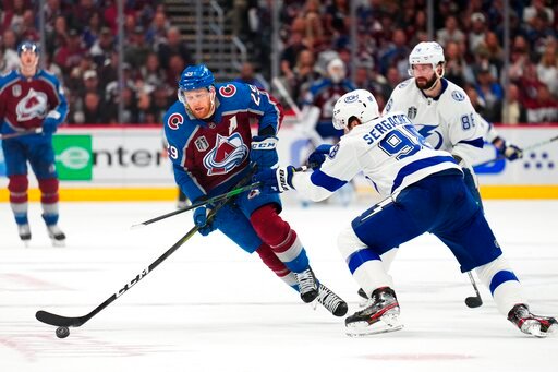 Colorado Avalanche center Nathan MacKinnon (29) moves the puck against Tampa Bay Lightning defenseman Mikhail Sergachev (98) during the second period in Game 5 of the NHL hockey Stanley Cup Final, Friday, June 24, 2022, in Denver. (AP Photo/Jack Dempsey)