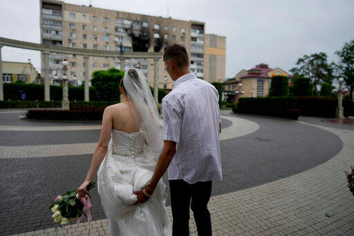 Yevhen Levchenko and Nadiia Prytula leave after getting married in Irpin, on the outskirts of Kyiv, Ukraine, Tuesday, June 21, 2022. After the wedding the couple must separate, Nadiia goes to study abroad and Yevhen stays because men cannot leave the country. A growing number of couples in Ukraine are speedily turning love into matrimony because of the war with Russia. Some are soldiers, marrying just before they head off to fight. Others are united in determination that living and loving to the full are more important than ever in the face of death and destruction. (AP Photo/Natacha Pisarenko)