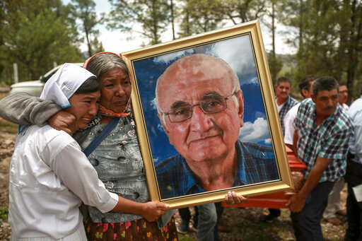 Women hold a portrait of Jesuit priest Javier Campos Morales as the funeral procession of Morales and fellow priest Joaquin Cesar Mora Salazar arrives to Cerocahui, Chihuahua state, Mexico, Sunday, June 26, 2022. The two elderly priests and a tour guide murdered in Mexico's Sierra Tarahumara this week are the latest in a long line of activists, reporters, travelers and local residents who have been threatened or killed by criminal gangs that dominate the region. (AP Photo/Christian Chavez)