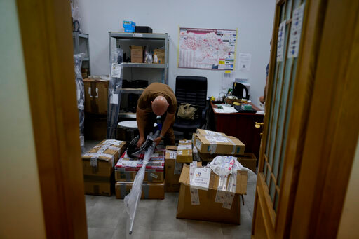A volunteer prepares boxes of goods to be delivered to soldiers fighting on the eastern and southern fronts, dispatched from an NGO storage center in Kyiv, Ukraine, Monday, June 13, 2022. In the war in Ukraine, troops on both sides are getting supplies from crowd-funders. On the Ukrainian side, the self-starting networks of donors and volunteers are particularly large, spontaneous and well-oiled. At a critical juncture of the invasion, their deliveries of drones, high-tech optical gear, vehicles and other equipment are keeping Ukraine in the fight against its better-supplied aggressor. (AP Photo/Natacha Pisarenko)