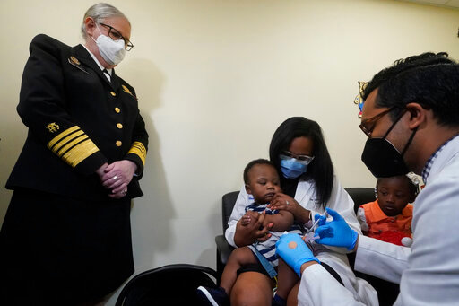 Pediatrician Emy Jean-Marie, center, holds her nine-month-old son Adedeji Adebayo, Emiola Adebayo, 3, on her lap as Dr. Nizar Dowla, right, administers a vaccine while &nbsp;&nbsp;&nbsp;&nbsp;&nbsp;&nbsp; Department of Health and Human Services Assistant Secretary for Health, Admiral Rachel Levine, left, looks on, Tuesday, June 28, 2022, at the Borinquen Health Care Center in Miami. Florida is the only state that didn't pre-order the under-5 vaccine, and state Surgeon General Joseph Ladapo has recommended against vaccinating healthy children. (AP Photo/Wilfredo Lee)