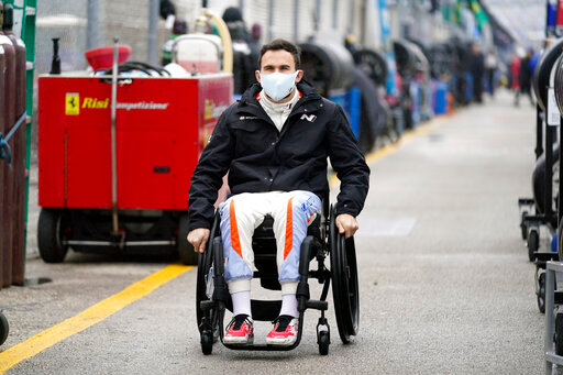 FILE - Robert Wickens makes his way to his pit stall during practice for the Rolex 24 hour auto race at Daytona International Speedway, Thursday, Jan. 27, 2022, in Daytona Beach, Fla. Wickens used hand controls last weekend to win his first race since a 2018 spinal cord injury temporarily ended his racing career. Across an ocean, former IndyCar driver Sam Schmidt and motorcycle racer Wayne Rainey also piloted vehicles during the annual Goodwood Festival of Speed in England. (AP Photo/John Raoux, File)