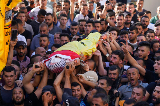 Palestinian mourners carry the body of Kamel Alawnah, who was shot by Israeli forces a day earlier, according to the Palestinian Ministry of Health, in the village of Jaba, near the West Bank city of Jenin, Sunday, July 3, 2022. The Israeli Defense Forces say a suspect hurled a Molotov cocktail at IDF soldiers in Jaba, who responded with live fire.  (AP Photo/Majdi Mohammed)