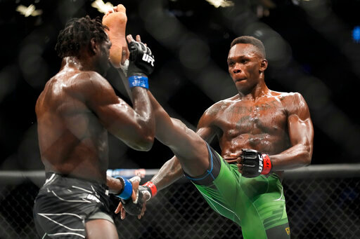 Israel Adesanya, right, kicks Jared Cannonier in a middleweight title bout during the UFC 276 mixed martial arts event Saturday, July 2, 2022, in Las Vegas. (AP Photo/John Locher)