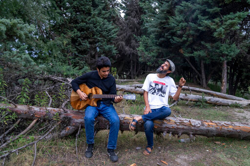 Kashmiri musicians Sarfaraz Javid, right, and Mohsin Hassan Bhat Jam on the outskirts of Srinagar, Indian Kashmir,  June 17, 2022. Musicians and artists in Kashmir are ordinary in life, each clutching onto the lived experiences of growing up in one of the world's most militarized zones that has known little but conflict for decades. But together, they embody a new form of music, a blend of progressive rock and hip hop that is an assertive expression of the region's political and cultural aspirations. (AP Photo/Dar Yasin)