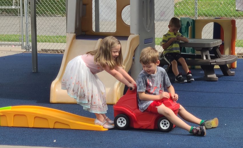 Pheobe Dunaway, left, pulls Brayden Murdock on a truck across the new smooth-surfaced playground at Pittsburg Community Child Care and Learning Center on Thursday.