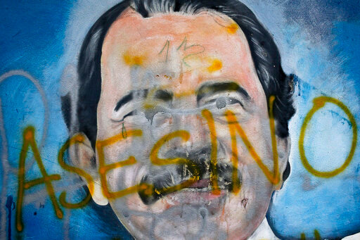 FILE - The Spanish word for &quot;Murderer&quot; covers a mural of Nicaragua's President Daniel Ortega, as part of anti-government protests demanding his resignation in Managua, Nicaragua, May 26, 2018. Four months before scheduled 2022 municipal elections, Nicaraguan riot police have taken over the city halls of five municipalities that had been in the hands of an opposition party. (AP Photo/Esteban Felix, File)