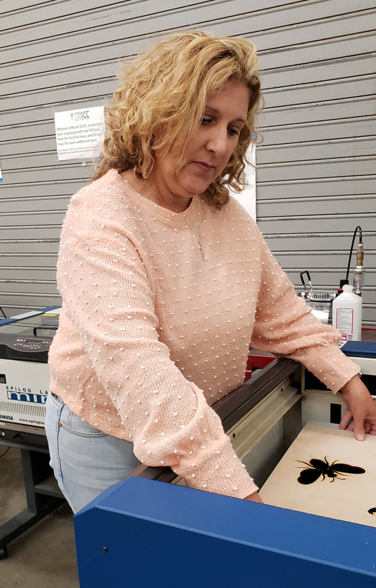 Creative marketer Joanne Smith, Independence, Kan., sets up a laser cutter in the maker space at Independence Community College, where she is making signs for a client's wedding reception.