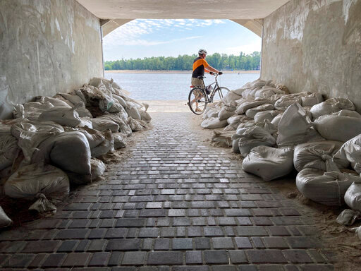 A Sunday morning cyclist emerges from a sandbagged tunnel next to the Dnipro River in Kyiv, Ukraine, Sunday, July 10, 2022. The war's reminders are everywhere as Russian forces pound away at communities in Ukraine's industrial heartland to the east. (AP Photo/Cara Anna)