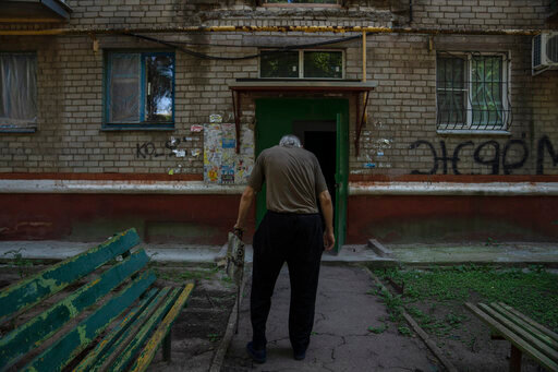 Seventy-year-old pensioner Valerii Ilchenko, who lives alone and is refusing to evacuate, walks to his apartment, after filling out his daily crossword, in Kramatorsk, eastern Ukraine, Wednesday, July 6, 2022. Now a widower, Ilchenko says he still has no intention of leaving. &quot;I don't have anywhere to go and don't want to either. What would I do there? Here at least I can sit on the bench, I can watch TV,&quot; he says in an interview in his single-room apartment. (AP Photo/Nariman El-Mofty)