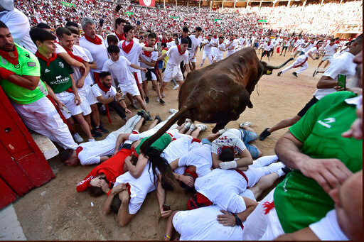 A fighting bull jumps over runners entering the bullring during the running of the bulls at the San Fermin Festival in Pamplona, northern Spain, Tuesday, July 12, 2022. Revellers from around the world flock to Pamplona every year for nine days of uninterrupted partying in Pamplona's famed running of the bulls festival which was suspended for the past two years because of the coronavirus pandemic. (AP Photo/Alvaro Barrientos)