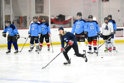 FILE - United States hockey player Haley Skarupa, front, demonstrates a drill during a hockey clinic presented by the Washington Capitals and the Professional Women's Hockey Players Association, Friday, March 4, 2022, in Arlington, Va. Montreal is finally getting its long-promised women&rsquo;s pro hockey franchise, though the Premier Hockey Federation put the brakes on adding a second expansion team entering its eighth season, the league announced Tuesday, July 12, 2022. (AP Photo/Nick Wass, File)