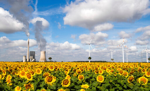 FILE - A field of sunflowers is within sight of the Mehrum coal-fired power station, wind turbines and high-voltage lines in Mehrum, Germany, Monday, Aug. 3, 2020. Chancellor Olaf Scholz says Germany&rsquo;s decision to reactivate coal and oil-fired power plants to relieve energy shortages because of the war in Ukraine is only temporary and his government remains committed to doing &ldquo;everything&rdquo; to combat the climate crisis. (Julian Stratenschulte/dpa via AP, File)