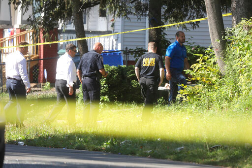Rochester police investigate behind a house on the corner of Bauman and Laser Streets where two police officers were shot last night in this area in Rochester, N.Y., on Friday, July 22, 2022.  (Tina MacIntyre-Yee/Democrat &amp; Chronicle via AP)