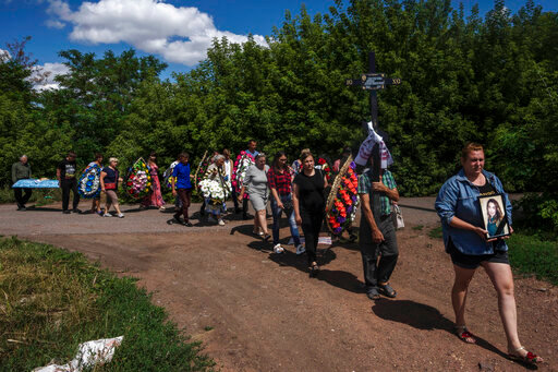Family and friends of 35-year-old Anna Protsenko, who was killed in a Russian rocket attack, walk to a cemetery for her burial, during her funeral procession, on the outskirts of Pokrovsk, eastern Ukraine, Monday, July 18, 2022. Protsenko was killed two days after coming home. She had done what authorities wanted, evacuating eastern Ukraine's Donetsk region as Russian forces move closer, but starting a new life elsewhere was uncomfortable and expensive. (AP Photo/Nariman El-Mofty)