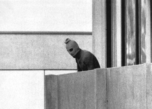 FILE - A member of the Arab Commando group which seized members of the Israeli Olympic Team at their quarters at the Olympic Village appearing with a hood over his face stands on the balcony of the building where the commandos held members of the Israeli team hostage in Munich, Sept. 5, 1972. The German government indicated Wednesday that it is willing to pay further compensation for the families of the Israeli athletes killed in an attack at the 1972 Munich Olympics following decades-long criticism from relatives over how Germany handled the attack and its aftermath. (AP Photo/Kurt Strumpf, File)
