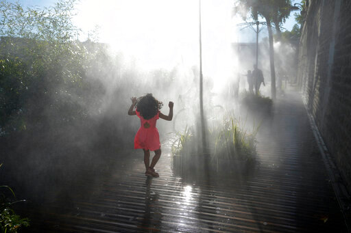 A kid walks along fresh water fogger system along the Seine river, as Europe is under an unusually extreme heat wave, in Paris, France, Tuesday, Aug. 2, 2022. (AP Photo/Francois Mori)